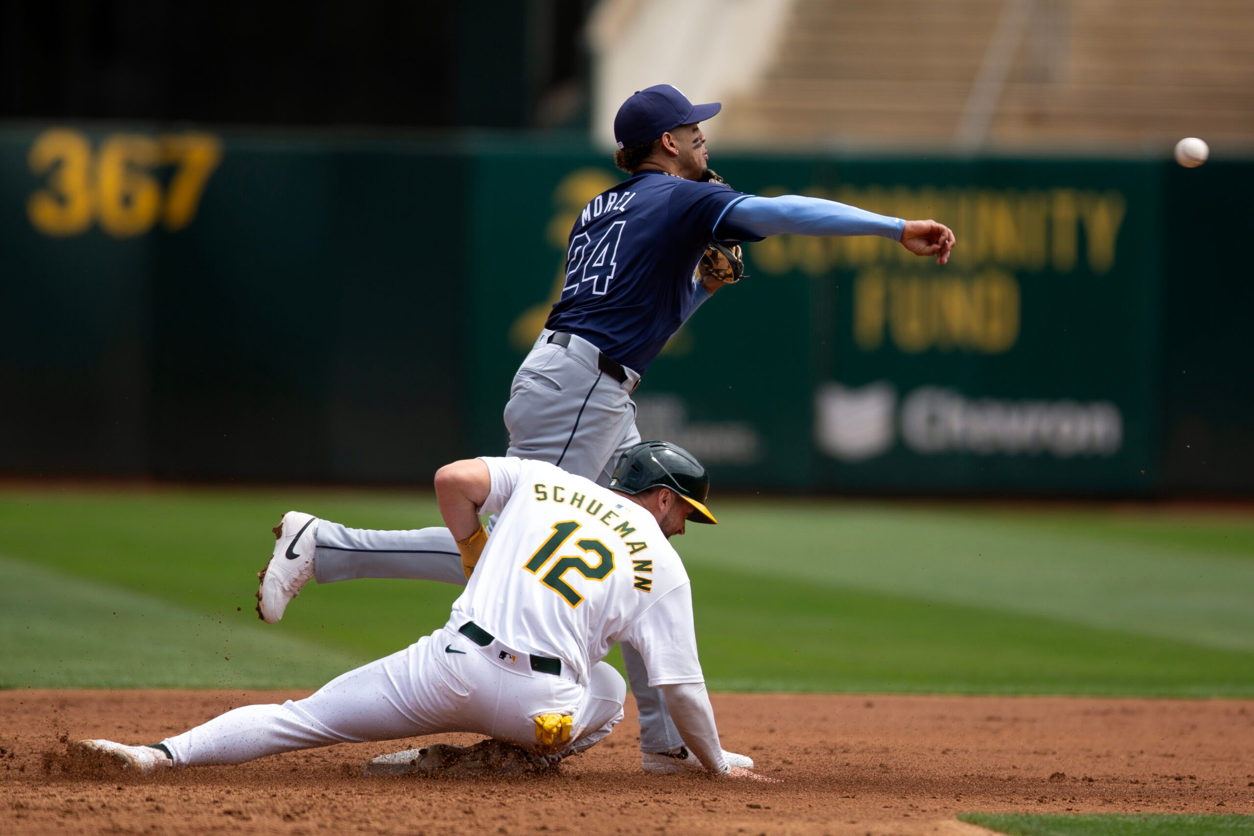 Aug 22, 2024; Oakland, California, USA; Tampa Bay Rays second baseman Christopher Morel (24) throws over Oakland Athletics shortstop Max Schuemann (12) to complete a double play during the second inning at Oakland-Alameda County Coliseum. Mandatory Credit: D. Ross Cameron-Imagn Images