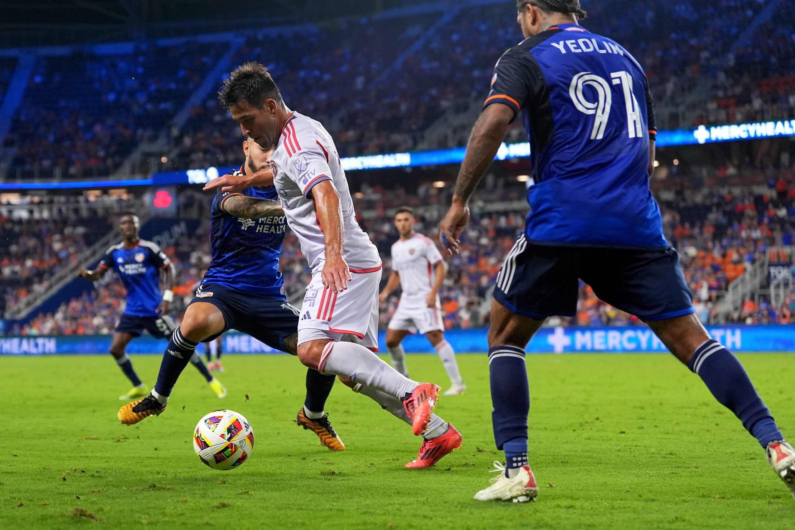 Oct 5, 2024; Cincinnati, Ohio, USA; Orlando City SC midfielder Nico Lodeiro (14) dribbles as FC Cincinnati midfielder Luciano Acosta (10) and FC Cincinnati defender DeAndre Yedlin (91) defend during the second half at TQL Stadium. Mandatory Credit: Kareem Elgazzar-Imagn Images