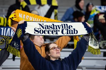 Feb 22, 2025; Nashville, Tennessee, USA; A Nashville SC fan holds up a scarf at the end of the match against New England Revolution at Geodis Park. Mandatory Credit: Kindell Buchanan-Imagn Images