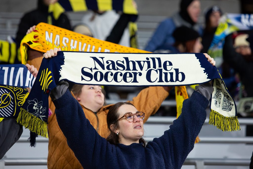 Feb 22, 2025; Nashville, Tennessee, USA; A Nashville SC fan holds up a scarf at the end of the match against New England Revolution at Geodis Park. Mandatory Credit: Kindell Buchanan-Imagn Images