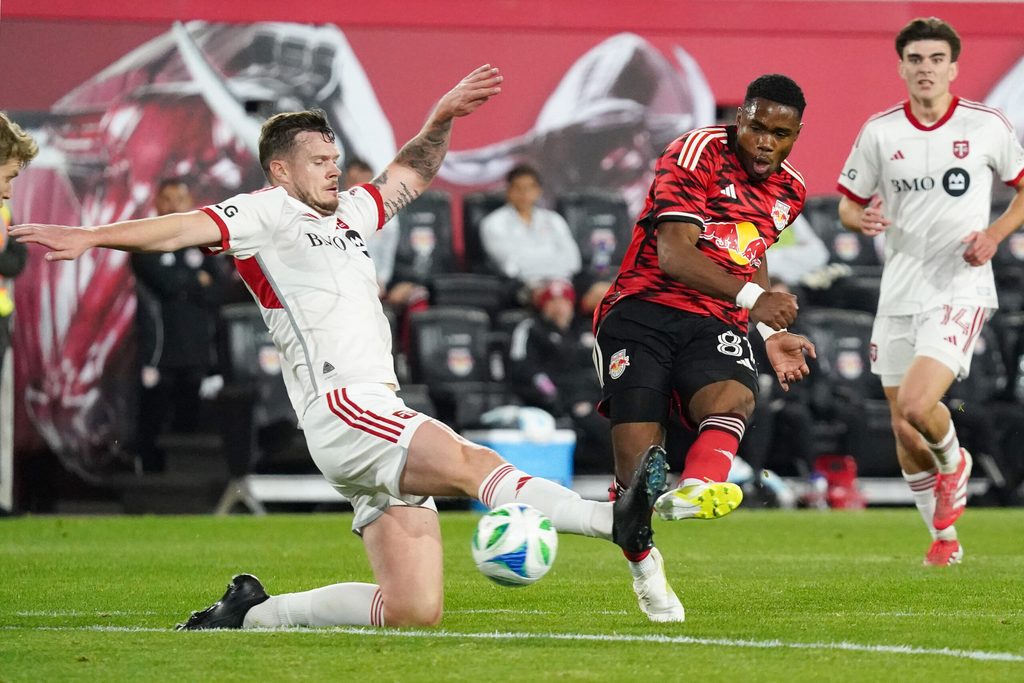 Mar 22, 2025; Harrison, New Jersey, USA; New York Red Bulls forward Serge Ngoma (81) shoots on goal as Toronto FC defender Kevin Long (5) defends during the second half at Sports Illustrated Stadium. Mandatory Credit: Lucas Boland-Imagn Images