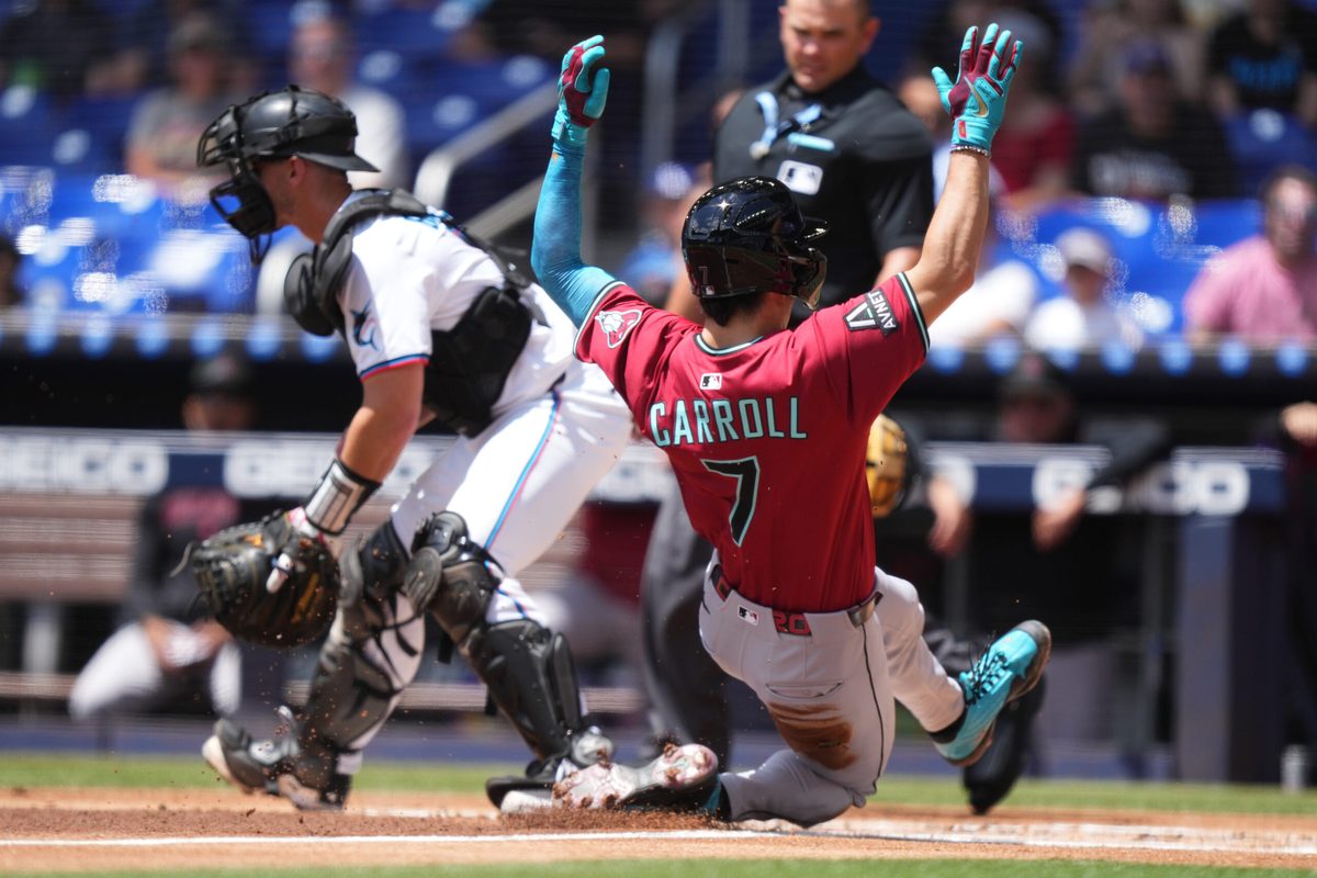Apr 17, 2025; Miami, Florida, USA; Arizona Diamondbacks right fielder Corbin Carroll (7) scores a run as Miami Marlins catcher Rob Brantly (19) looks on at loanDepot Park. Mandatory Credit: Jim Rassol-Imagn Images