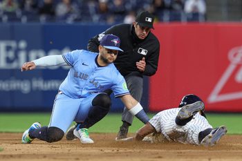 Apr 27, 2025; Bronx, New York, USA; Toronto Blue Jays shortstop Bo Bichette (11) tags out New York Yankees shortstop Anthony Volpe (11) on a steal attempt at second base during the eighth inning at Yankee Stadium. Mandatory Credit: Vincent Carchietta-Imagn Images