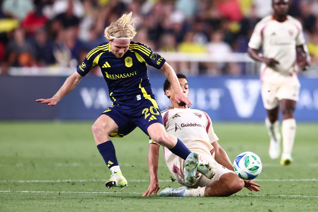 May 17, 2025; Nashville, Tennessee, USA; Nashville SC midfielder Edvard Tagseth (20) is slide tackled by D.C. United midfielder Brandon Servania (23) in the second half at Geodis Park. Mandatory Credit: Casey Gower-Imagn Images