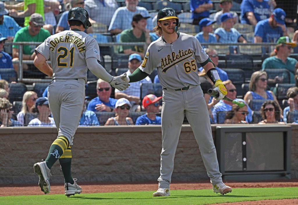 Jun 14, 2025; Kansas City, Missouri, USA; Athletics left fielder Tyler Soderstrom (21) gets a hand from catcher Willie Maclver (65) after scoring a run in the fourth inning against the Kansas City Royals at Kauffman Stadium. Mandatory Credit: Peter Aiken-Imagn Images