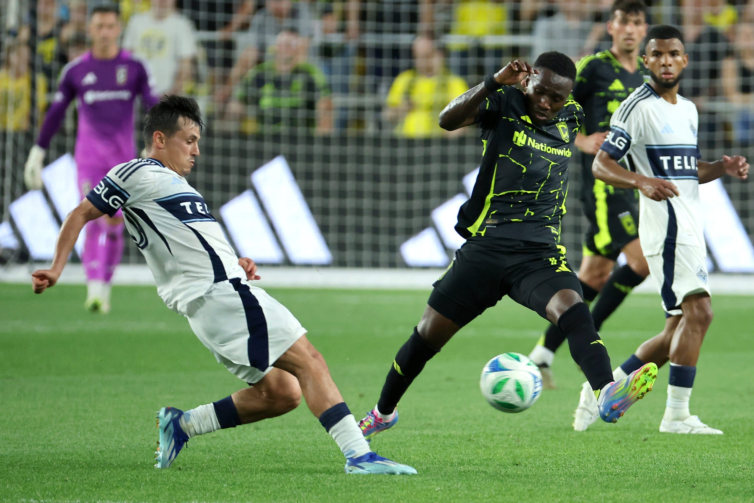 Jun 14, 2025; Columbus, Ohio, USA;  Columbus Crew forward Ibrahim Aliyu (11) kicks the ball past Vancouver Whitecaps midfielder Andrés Cubas (20) during the second half at Lower.com Field. Mandatory Credit: Joseph Maiorana-Imagn Images