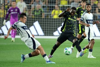 Jun 14, 2025; Columbus, Ohio, USA;  Columbus Crew forward Ibrahim Aliyu (11) kicks the ball past Vancouver Whitecaps midfielder Andrés Cubas (20) during the second half at Lower.com Field. Mandatory Credit: Joseph Maiorana-Imagn Images
