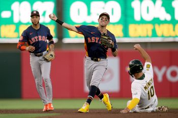 Jun 18, 2025; West Sacramento, California, USA; Houston Astros second baseman Mauricio Dubon (14) turns a double play over the top of Athletics third baseman Max Muncy (10) in the fourth inning at Sutter Health Park. Mandatory Credit: Cary Edmondson-Imagn Images