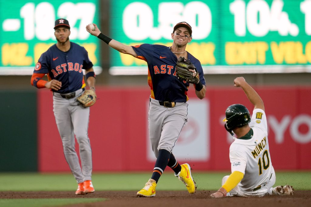 Jun 18, 2025; West Sacramento, California, USA; Houston Astros second baseman Mauricio Dubon (14) turns a double play over the top of Athletics third baseman Max Muncy (10) in the fourth inning at Sutter Health Park. Mandatory Credit: Cary Edmondson-Imagn Images