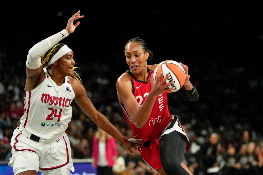Jun 26, 2025; Las Vegas, Nevada, USA; Las Vegas center A'ja Wilson (22) drives the ball against Washington Mystics forward Aaliyah Edwards (24) during the first half of a WNBA basketball game at Michelob Ultra Arena. Mandatory Credit: Lucas Peltier-Imagn Images