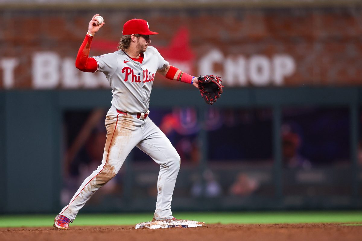 Jun 27, 2025; Atlanta, Georgia, USA; Philadelphia Phillies second baseman Bryson Stott (5) turns a double play against the Atlanta Braves in the fifth inning at Truist Park. Mandatory Credit: Brett Davis-Imagn Images