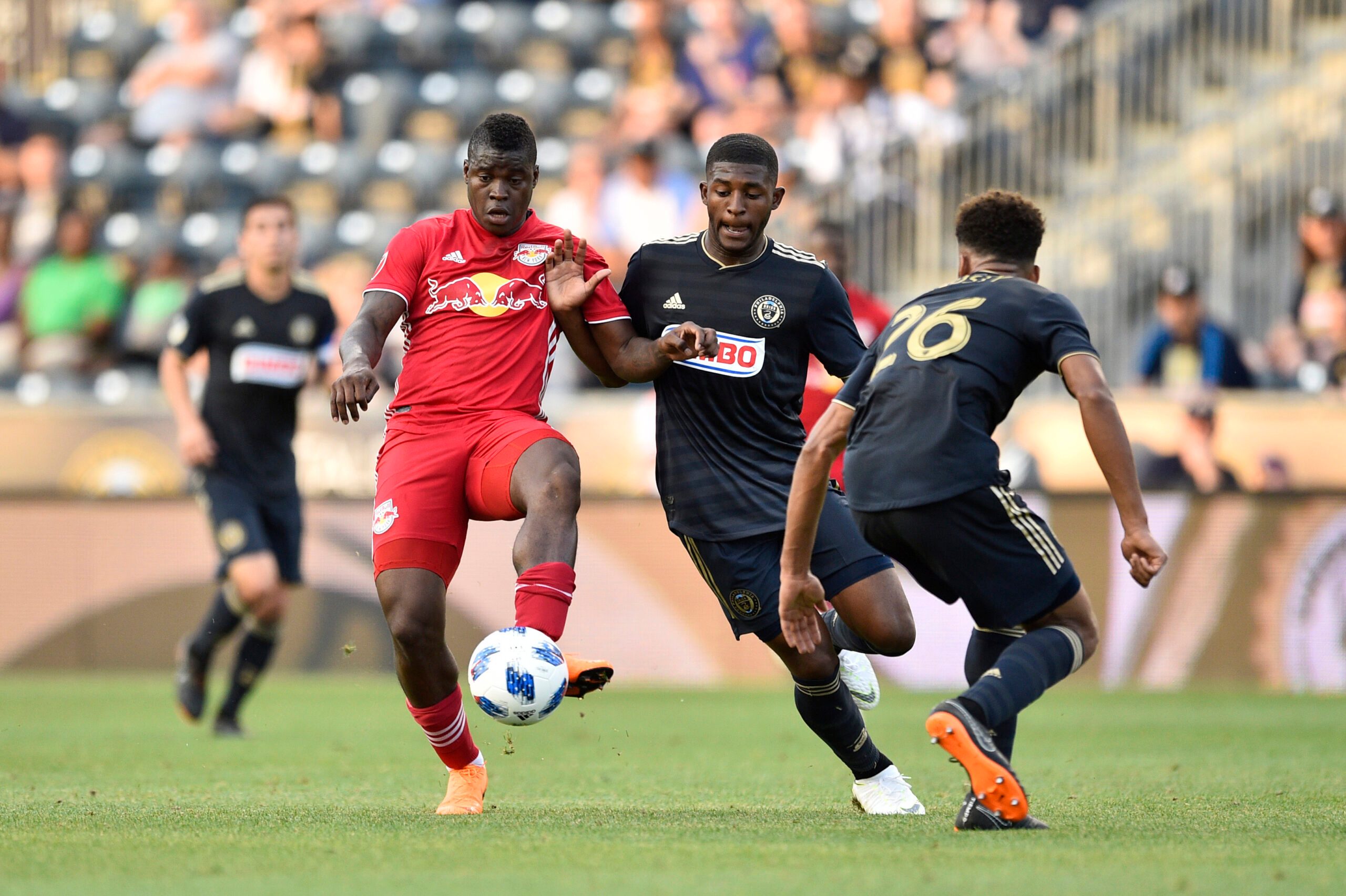 Jun 16, 2018; Philadelphia, PA, USA; New York Red Bulls forward Carlos Rivas (left) plays the ball against Philadelphia Union defender Mark McKenzie (middle) and defender Auston Trusty (26) during the first half at Talen Energy Stadium. Mandatory Credit: Derik Hamilton-Imagn Images