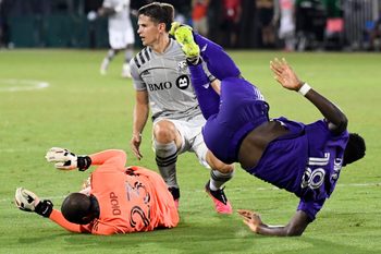 Jul 25, 2020; Orlando, Florida, USA; Orlando City SC forward Daryl Dike (18) dribbles the ball as Montreal Impact defender Jukka Raitala (22) tackles and goalkeeper Clement Diol (23) defends during the second half at ESPN Wide World of Sports Complex. Mandatory Credit: Douglas DeFelice-Imagn Images