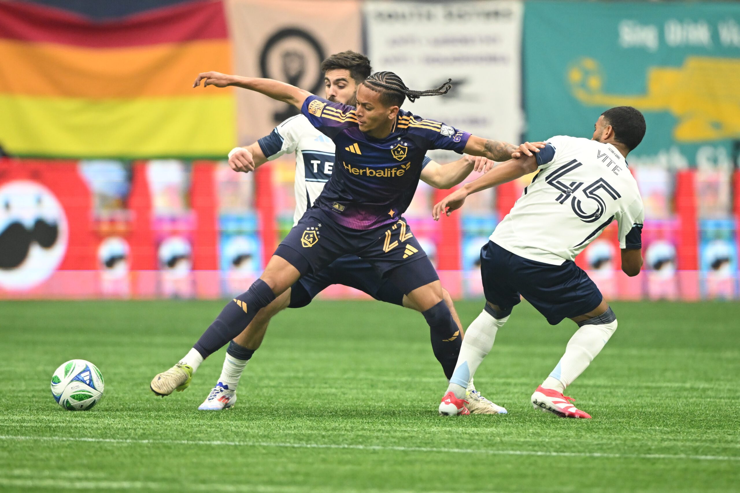 Mar 2, 2025; Vancouver, British Columbia, CAN; LA Galaxy midfielder Elijah Wynder (22) reaches for the ball against Vancouver Whitecaps FC midfielder Pedro Vite (45) during the second half at BC Place. Mandatory Credit: Anne-Marie Sorvin-Imagn Images