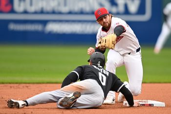 Apr 10, 2025; Cleveland, Ohio, USA; Chicago White Sox designated hitter Nick Maton (0) dives back to second as Cleveland Guardians second baseman Daniel Schneemann (10) is late with the tag during the first inning at Progressive Field. Mandatory Credit: Ken Blaze-Imagn Images