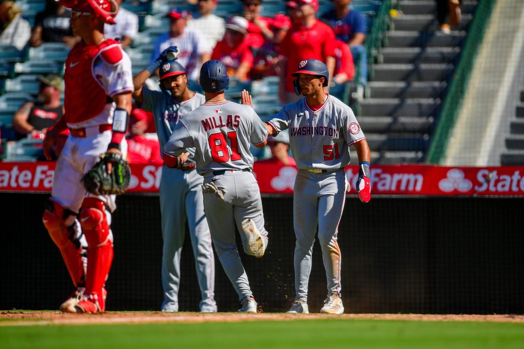 Jun 29, 2025; Anaheim, California, USA; Washington Nationals catcher Drew Millas (81) and right fielder Daylen Lile (51) score runs against the Los Angeles Angels during the eleventh inning at Angel Stadium. Mandatory Credit: Gary A. Vasquez-Imagn Images