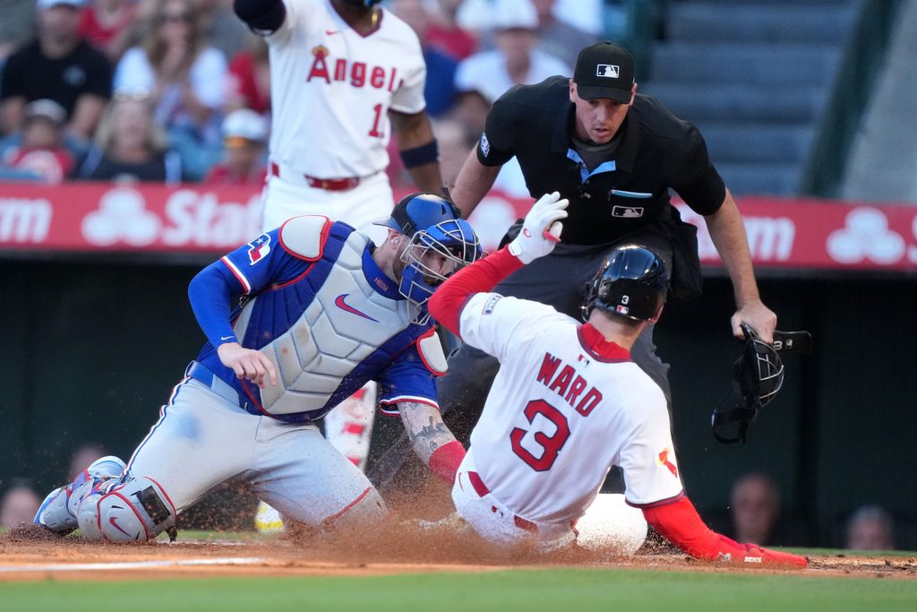 Jul 10, 2025; Anaheim, California, USA; Los Angeles Angels left fielder Taylor Ward (3) is tagged out at home plate by Texas Rangers catcher Jonah Heim (28) as home plate umpire Nate Tomlinson makes the call in the first inning at Angel Stadium. Mandatory Credit: Kirby Lee-Imagn Images