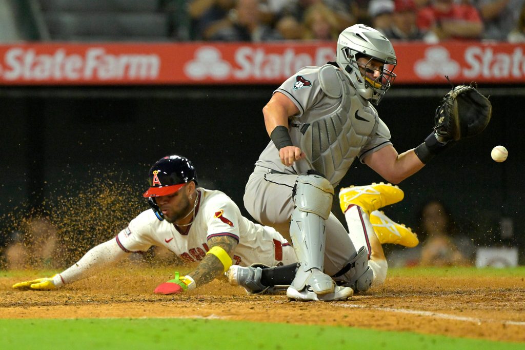 Jul 12, 2025; Anaheim, California, USA; Los Angeles Angels third baseman Yoan Moncada (5) beats the throw to Arizona Diamondbacks as he scores on a single by shortstop Zach Neto (9) in the eighth inning at Angel Stadium. Mandatory Credit: Jayne Kamin-Oncea-Imagn Images