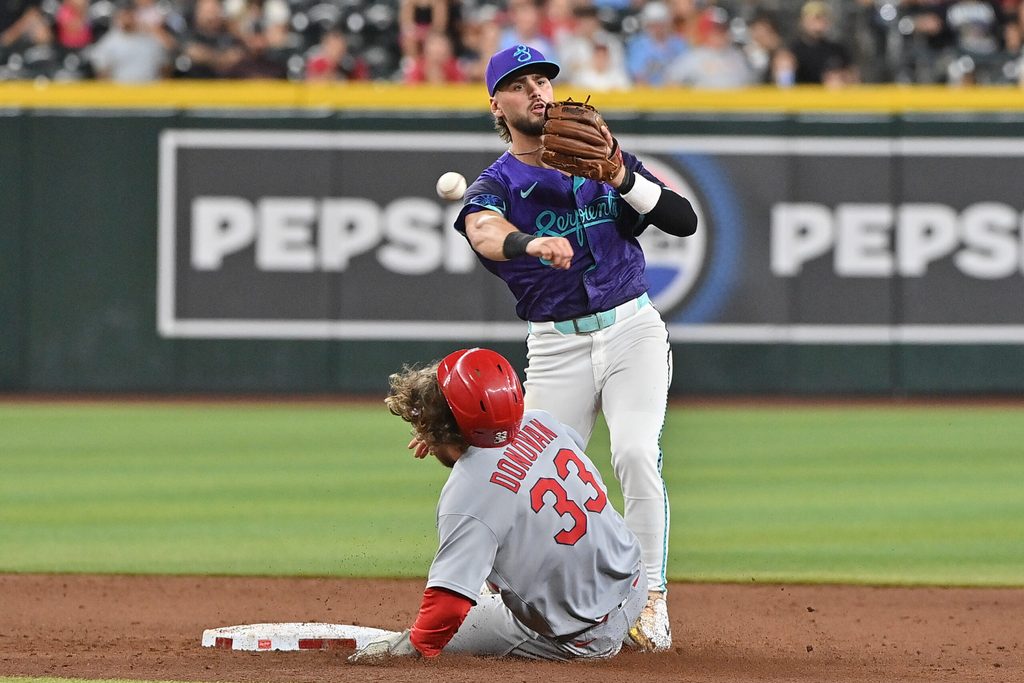Jul 18, 2025; Phoenix, Arizona, USA; Arizona Diamondbacks shortstop Blaze Alexander (9) turns a double play on St. Louis Cardinals second base Brendan Donovan (33) to tned the game in the ninth inning  at Chase Field. Mandatory Credit: Matt Kartozian-Imagn Images