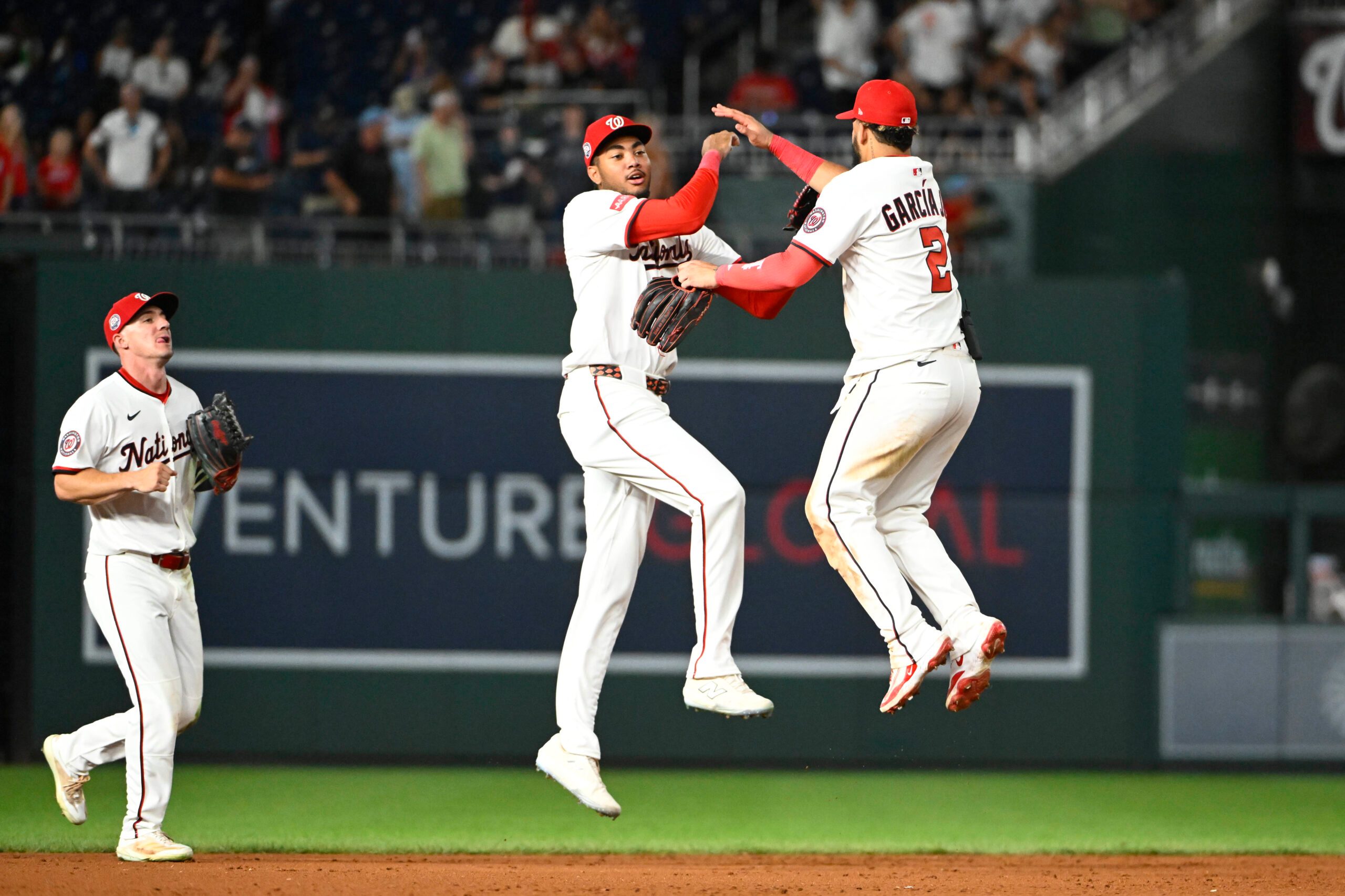 Jul 22, 2025; Washington, District of Columbia, USA; Washington Nationals left fielder James Wood (29) celebrates with  second baseman Luis Garcia Jr. (2) as center fielder Jacob Young (30) looks on after the game against the Cincinnati Reds at Nationals Park. Mandatory Credit: Brad Mills-Imagn Images