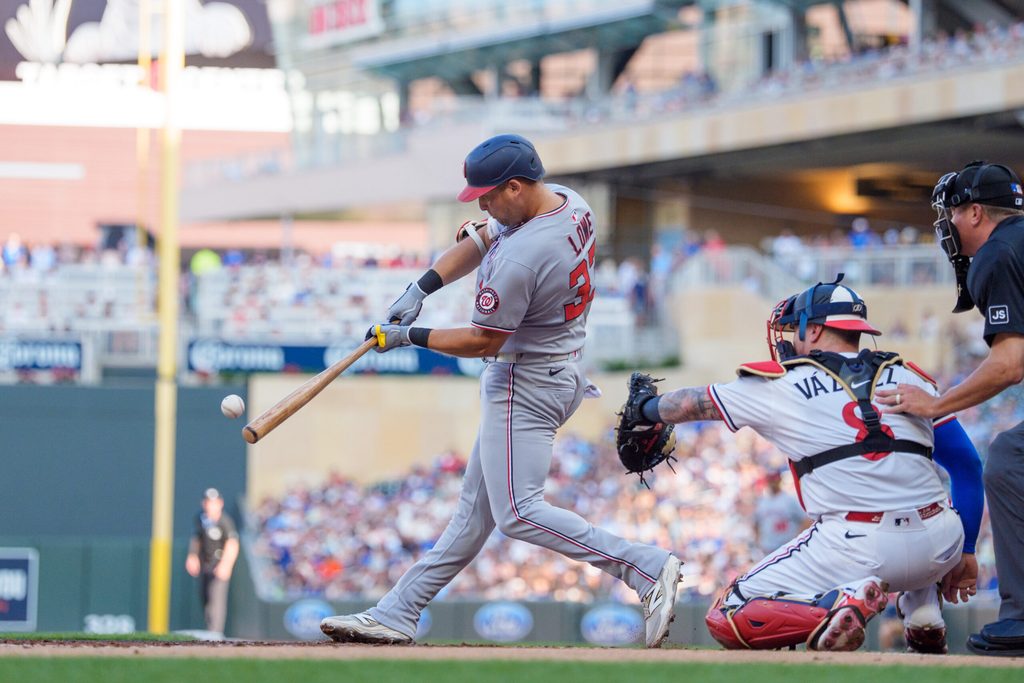Jul 26, 2025; Minneapolis, Minnesota, USA; Washington Nationals first baseman Nathaniel Lowe (33) connects with the ball in the first inning. Minnesota Twins shortstop Carlos Correa (4) would field the ball and throw him out at first at Target Field. Mandatory Credit: Matt Blewett-Imagn Images