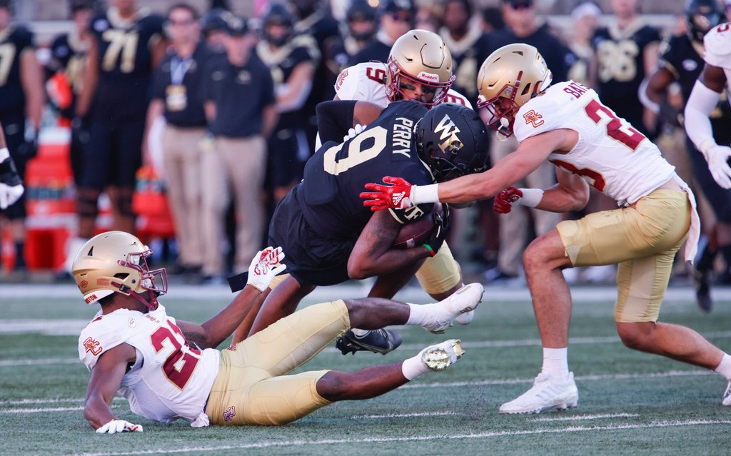 Oct 22, 2022; Winston-Salem, North Carolina, USA;  Boston College Eagles defensive back Josh DeBerry (bottom left) and defensive back Cole Batson (right) and defensive back Jaiden Woodbey (9) tackle Wake Forest Demon Deacons wide receiver A.T. Perry (9) during the second quarter at Truist Field. Mandatory Credit: Reinhold Matay-Imagn Images