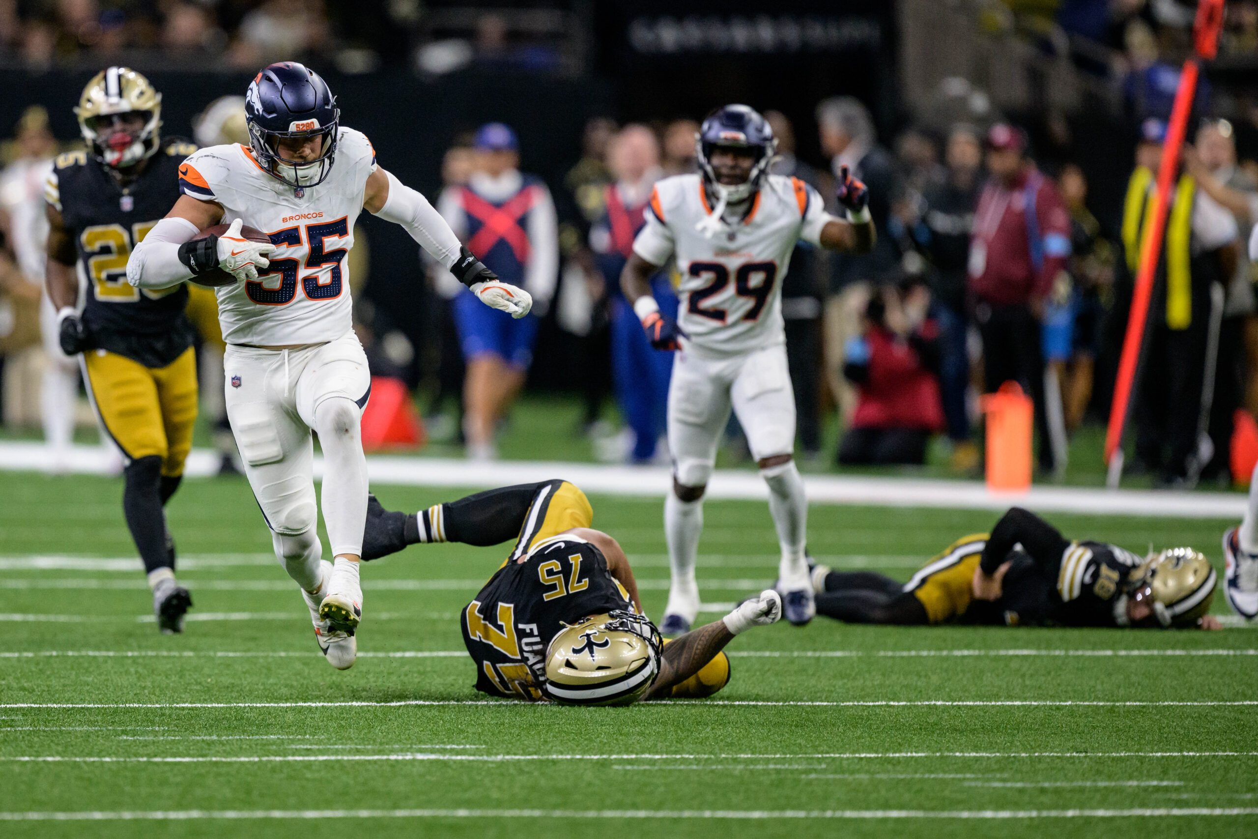 Oct 17, 2024; New Orleans, Louisiana, USA; Denver Broncos linebacker Cody Barton (55) runs back an interception for a touchdown against New Orleans Saints offensive tackle Taliese Fuaga (75) and New Orleans Saints quarterback Spencer Rattler, right, during the fourth quarter at Caesars Superdome. Mandatory Credit: Matthew Hinton-Imagn Images