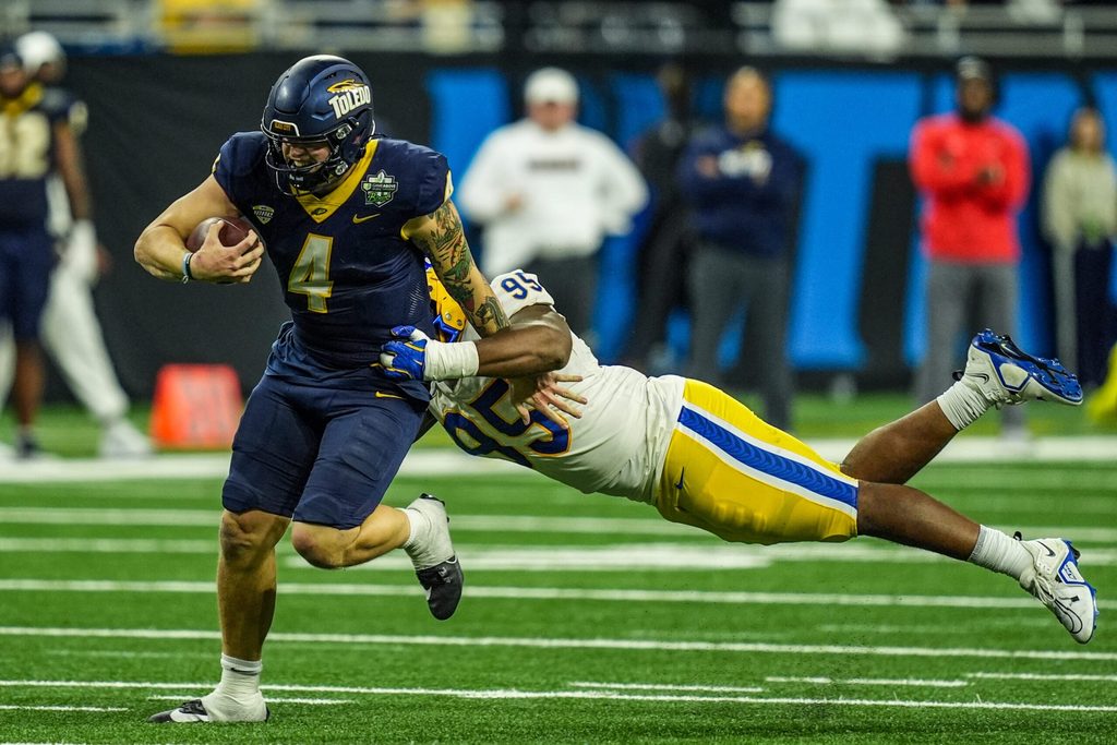 Toledo Rockets quarterback Tucker Gleason (4) avoids being tackled by Pittsburgh Panthers defensive lineman Francis Brewu (95), during one of the six overtimes in the 2024 GameAbove Sports Bowl at Ford Field in Detroit, on Thursday, Dec. 26, 2024.
