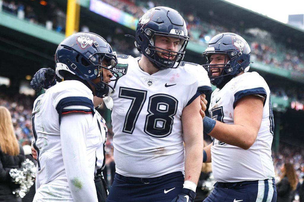 UConn's Skyler Bell, left, celebrates a touchdown with teammates Carsten Casady, center, and Christopher Fortin during the third annual Wasabi Fenway Bowl against North Carolina at Fenway Park on Saturday, Dec. 28, 2024.