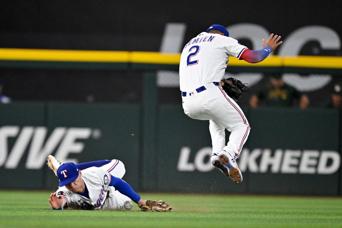 Jul 23, 2025; Arlington, Texas, USA; Texas Rangers center fielder Michael Helman (24) dives but cannot catch a ball hit by Athletics left fielder Miguel Andujar (not pictured) as second baseman Marcus Semien (2) attempts to get out of way during the sixth inning at Globe Life Field. Mandatory Credit: Jerome Miron-Imagn Images