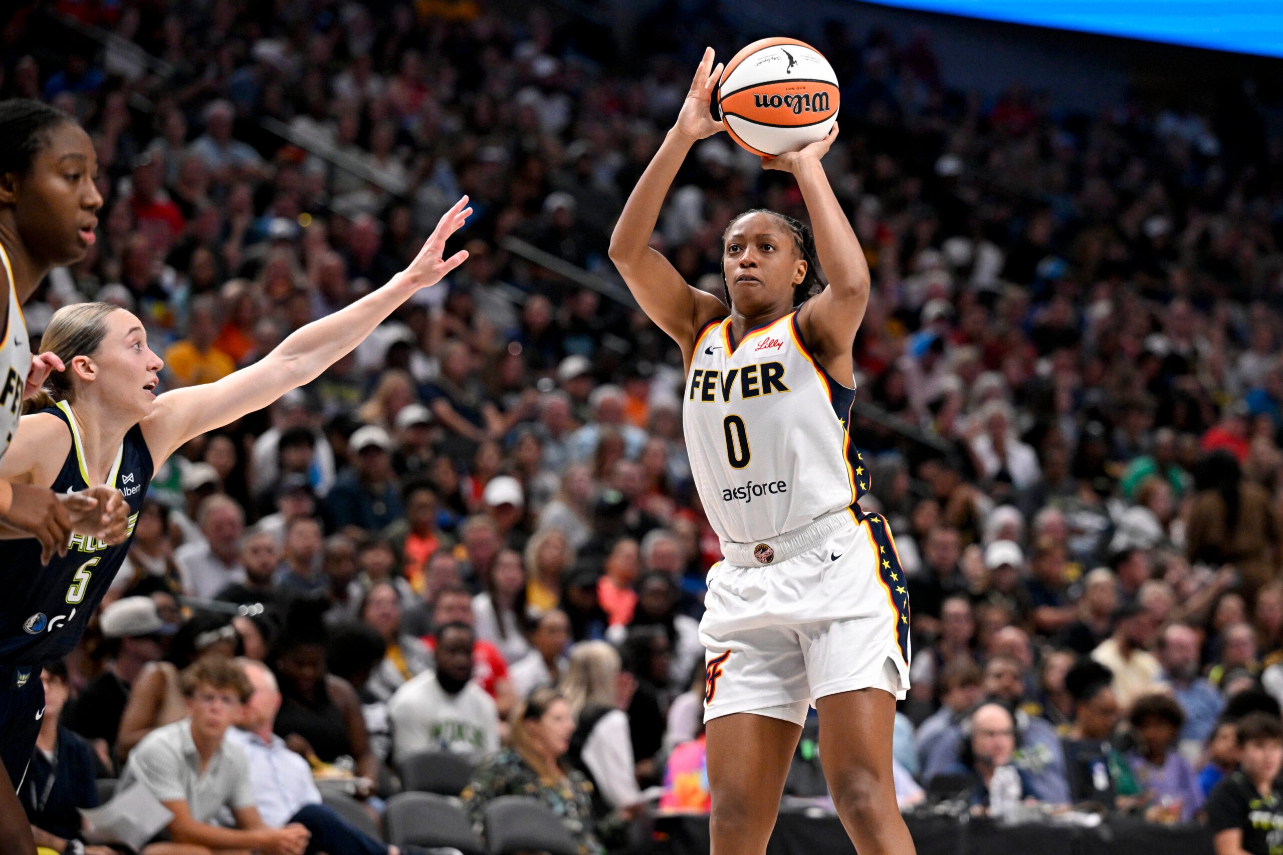 Aug 1, 2025; Dallas, Texas, USA;  Indiana Fever guard Kelsey Mitchell (0) makes a jump shot over Dallas Wings guard Paige Bueckers (5) during the second half at the American Airlines Center. Mandatory Credit: Jerome Miron-Imagn Images