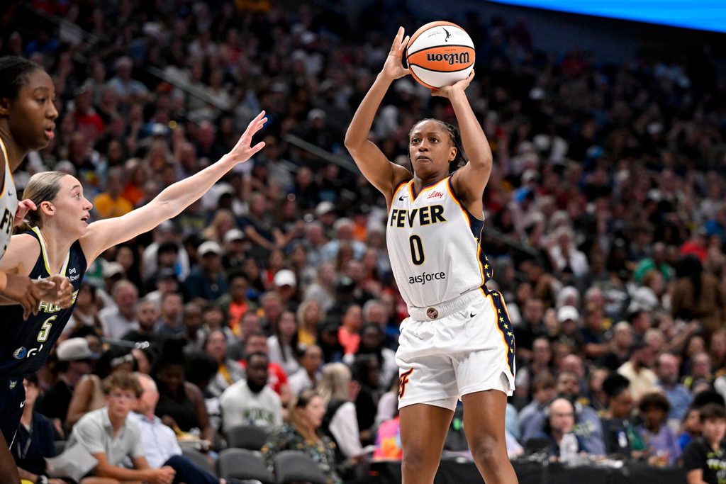 Aug 1, 2025; Dallas, Texas, USA; Indiana Fever guard Kelsey Mitchell (0) makes a jump shot over Dallas Wings guard Paige Bueckers (5) during the second half at the American Airlines Center. Mandatory Credit: Jerome Miron-Imagn Images