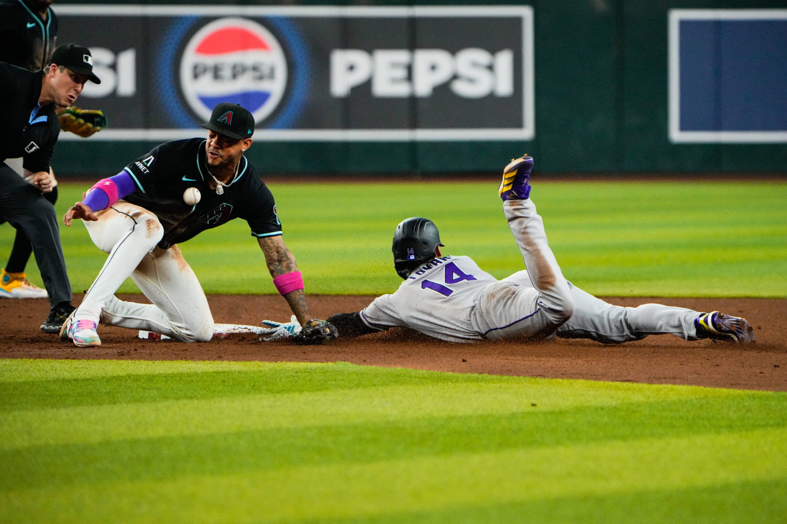 Aug 9, 2025; Phoenix, Arizona, USA;  Colorado Rockies shortstop Ezequiel Tovar (14) slides into second base while Arizona Diamondbacks shortstop Geraldo Perdomo (2) misses the throw in the third inning of the game between the Arizona Diamondbacks and Colorado Rockies at Chase Field. Mandatory Credit: Arianna Grainey-Imagn Images