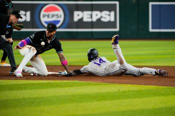 Aug 9, 2025; Phoenix, Arizona, USA;  Colorado Rockies shortstop Ezequiel Tovar (14) slides into second base while Arizona Diamondbacks shortstop Geraldo Perdomo (2) misses the throw in the third inning of the game between the Arizona Diamondbacks and Colorado Rockies at Chase Field. Mandatory Credit: Arianna Grainey-Imagn Images