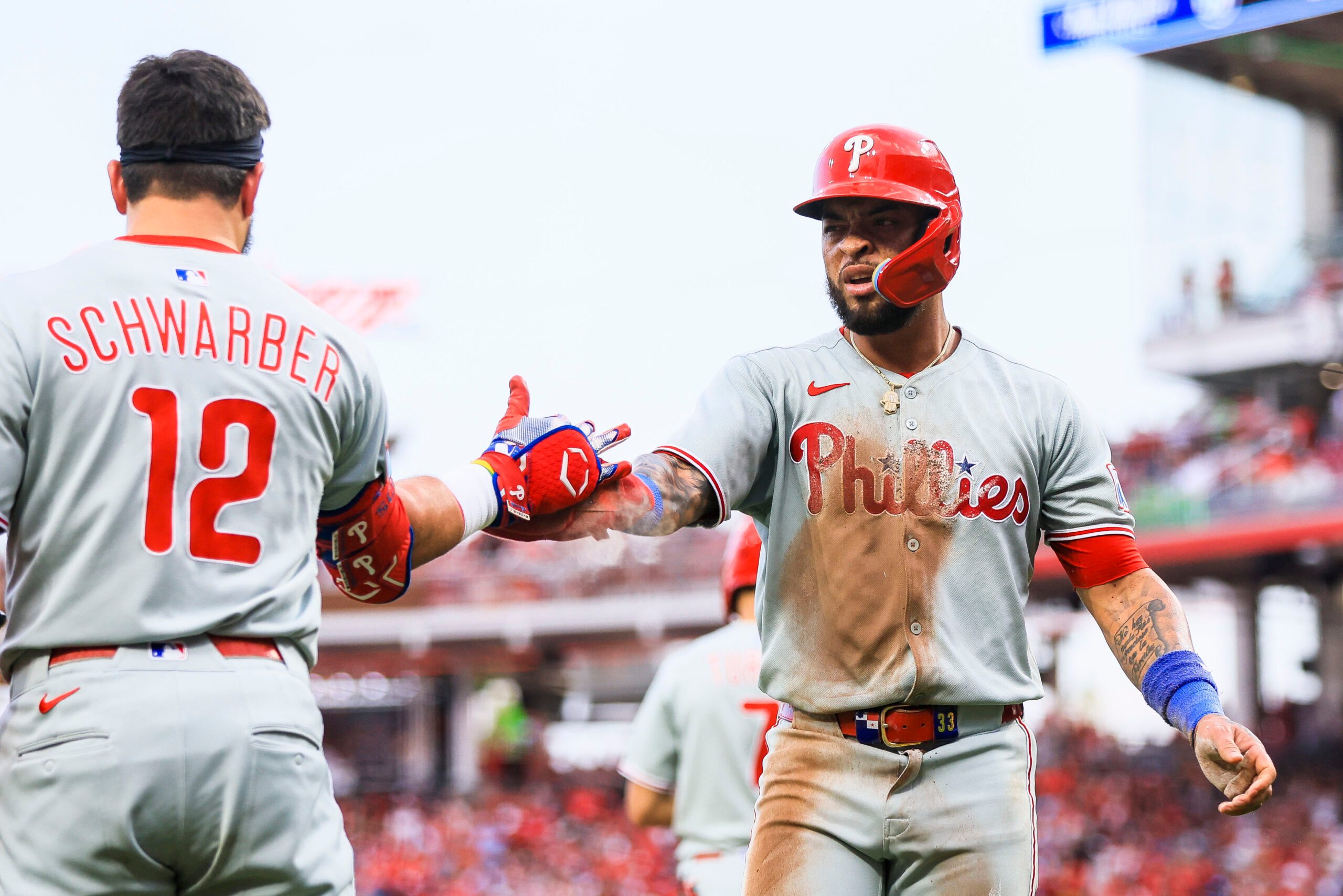 Aug 11, 2025; Cincinnati, Ohio, USA; Philadelphia Phillies second baseman Edmundo Sosa (33) high fives designated hitter Kyle Schwarber (12) after scoring on a double hit by outfielder Weston Wilson (not pictured) in the eighth inning against the Cincinnati Reds at Great American Ball Park. Mandatory Credit: Katie Stratman-Imagn Images