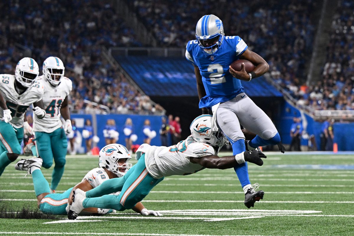 Aug 16, 2025; Detroit, Michigan, USA; Detroit Lions quarterback Hendon Hooker (2) scrambles away from Miami Dolphins linebacker Dequan Jackson (57) to score a touchdown that was nullified by an offensive penalty in the third quarter at Ford Field. Mandatory Credit: Lon Horwedel-Imagn Images