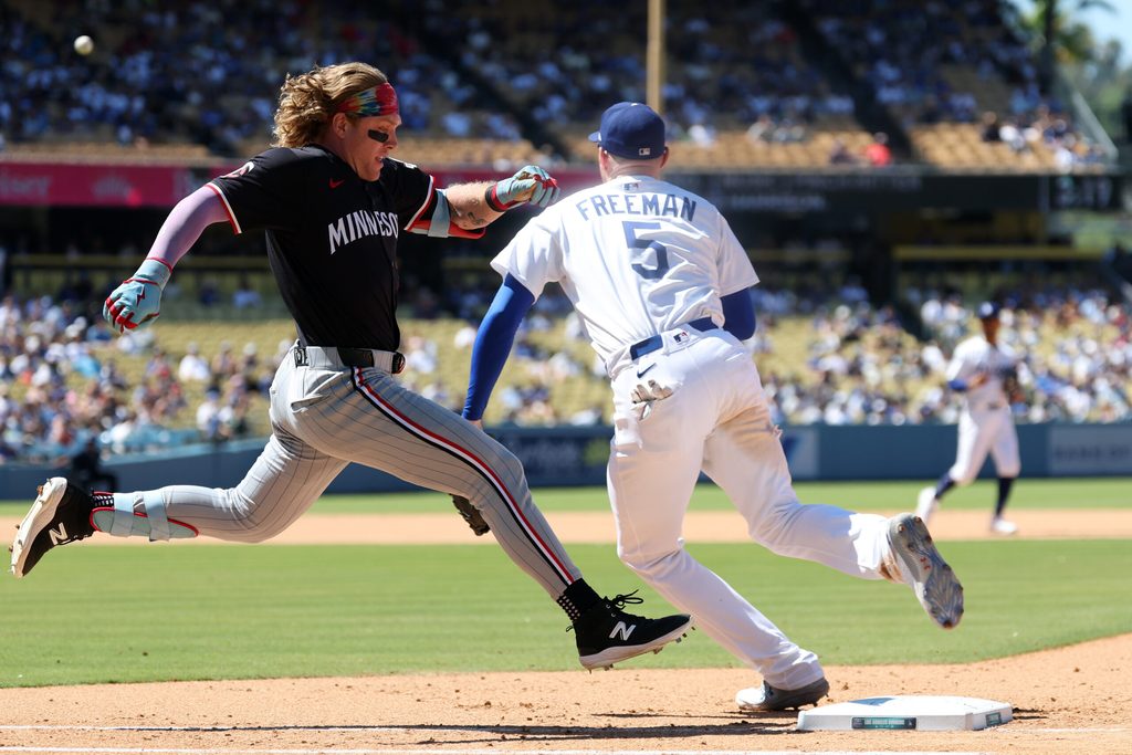 Jul 23, 2025; Los Angeles, California, USA; Minnesota Twins pinch hitter Harrison Bader (12) beats the throw to Los Angeles Dodgers first baseman Freddie Freeman (5) for an RBI single during the eighth inning at Dodger Stadium. Mandatory Credit: Kiyoshi Mio-Imagn Images