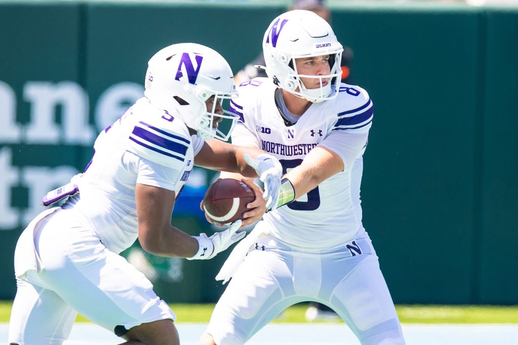 Aug 30, 2025; New Orleans, Louisiana, USA; Northwestern Wildcats quarterback Preston Stone (8) hands the ball off to running back Caleb Komolafe (5) against Tulane Green Wave during the second half at Yulman Stadium. Mandatory Credit: Stephen Lew-Imagn Images