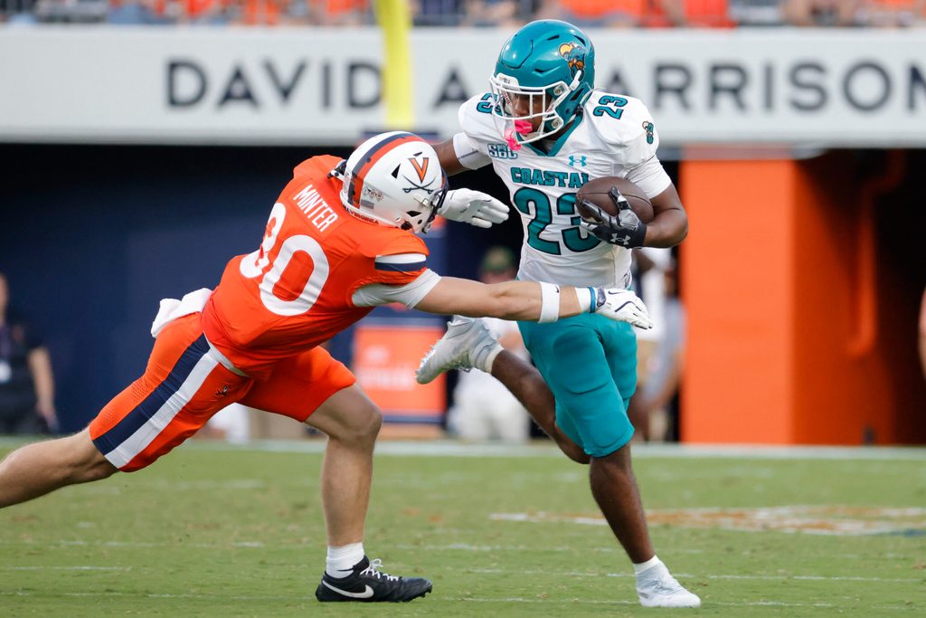Aug 30, 2025; Charlottesville, Virginia, USA; Coastal Carolina Chanticleers running back Dominic Knicely (23) carries the ball as Virginia Cavaliers safety Ethan Minter (30) during the second quarter at Scott Stadium. Mandatory Credit: Amber Searls-Imagn Images