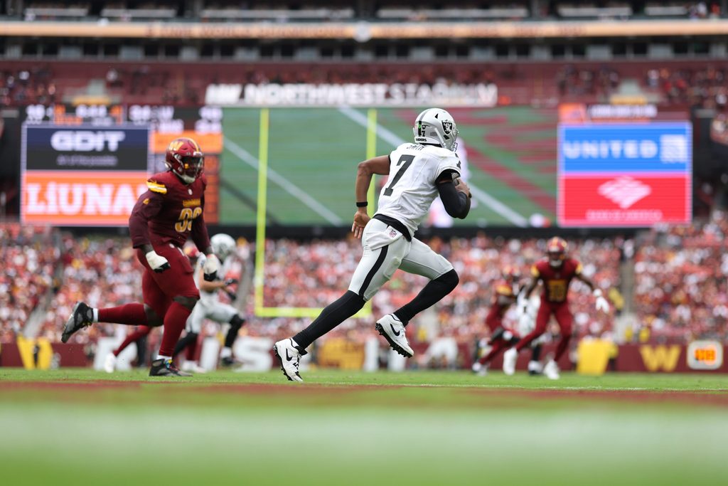 Sep 21, 2025; Landover, Maryland, USA; Las Vegas Raiders quarterback Geno Smith (7) scrambles from Washington Commanders defensive end Javontae Jean-Baptiste (90) during the fourth quarter at Northwest Stadium. Mandatory Credit: Geoff Burke-Imagn Images