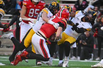 Nov 23, 2024; College Park, Maryland, USA;  Maryland Terrapins quarterback Billy Edwards Jr. (9) hits Iowa Hawkeyes defensive back Xavier Nwankpa (1) as defensive back Quinn Schulte (30) tackles during the second  half at SECU Stadium. Mandatory Credit: Tommy Gilligan-Imagn Images