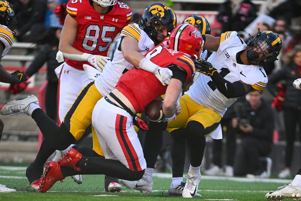 Nov 23, 2024; College Park, Maryland, USA; Maryland Terrapins quarterback Billy Edwards Jr. (9) hits Iowa Hawkeyes defensive back Xavier Nwankpa (1) as defensive back Quinn Schulte (30) tackles during the second half at SECU Stadium. Mandatory Credit: Tommy Gilligan-Imagn Images