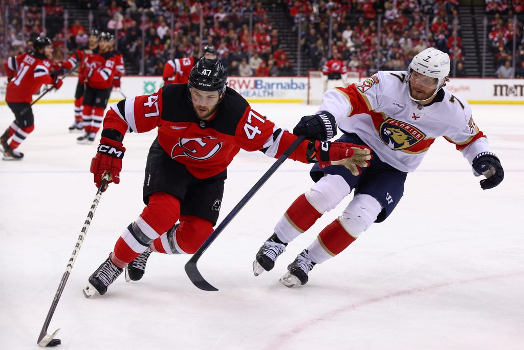 Jan 14, 2025; Newark, New Jersey, USA; New Jersey Devils center Paul Cotter (47) skates with the puck while being defended by Florida Panthers defenseman Dmitry Kulikov (7) during the second period at Prudential Center. Mandatory Credit: Ed Mulholland-Imagn Images