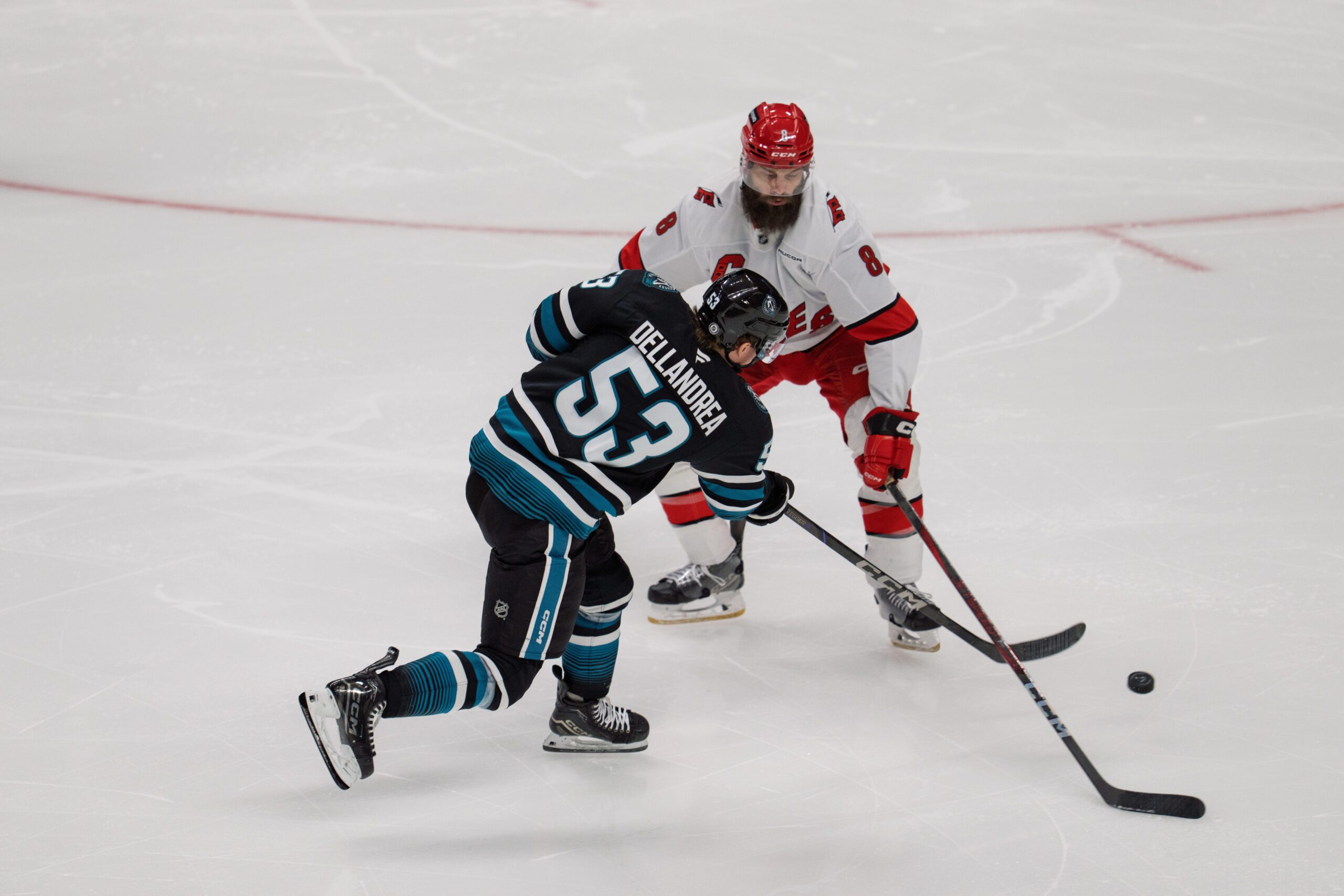 Mar 20, 2025; San Jose, California, USA; San Jose Sharks center Ty Dellandrea (53) shoots the puck against Carolina Hurricanes defenseman Brent Burns (8) during the third period at SAP Center at San Jose. Mandatory Credit: Neville E. Guard-Imagn Images