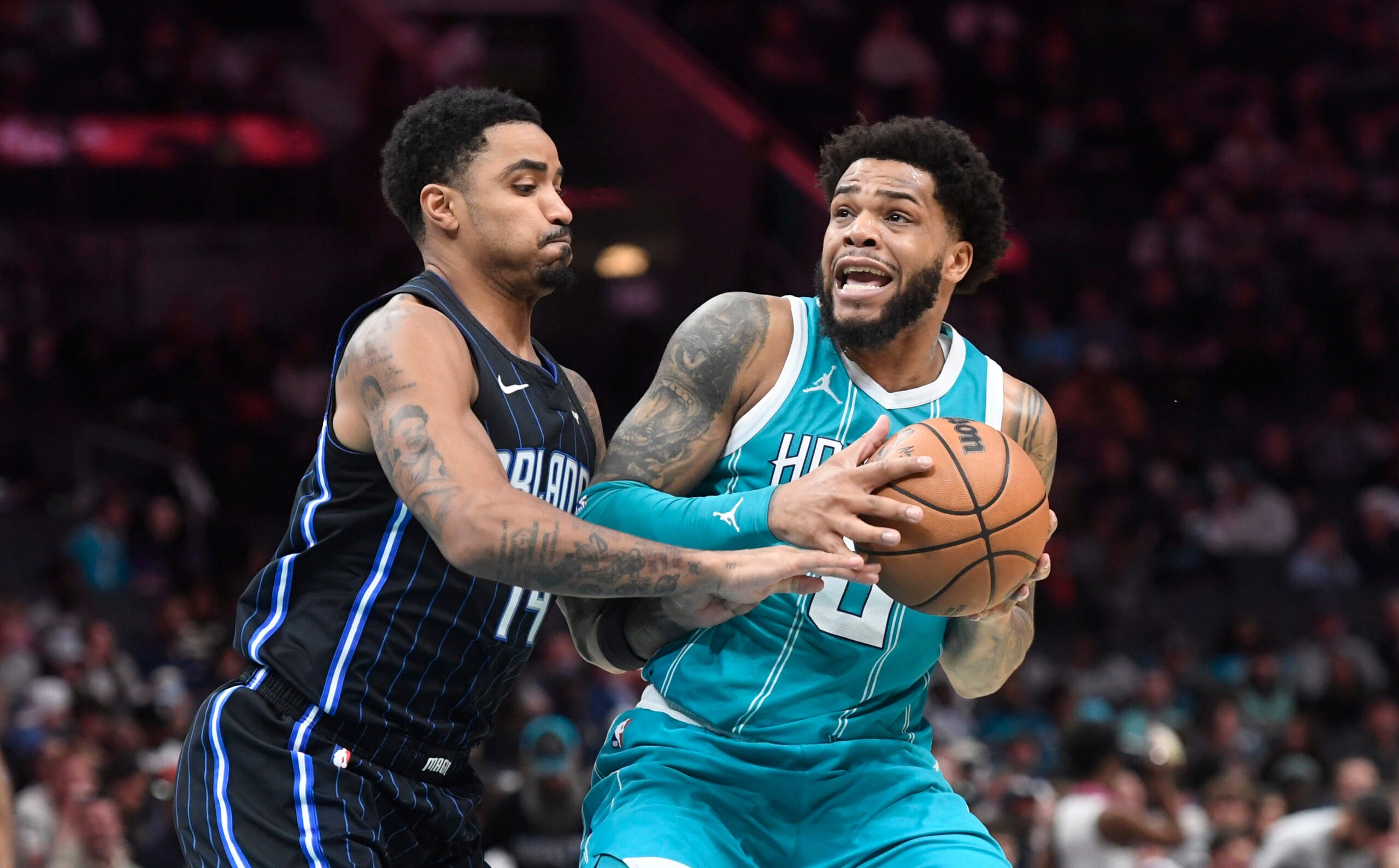 Mar 25, 2025; Charlotte, North Carolina, USA;  Charlotte Hornets forward Miles Bridges (0) looks to pass as he is defended by Orlando Magic guard Gary Harris (14) during the second half at the Spectrum Center. Mandatory Credit: Sam Sharpe-Imagn Images