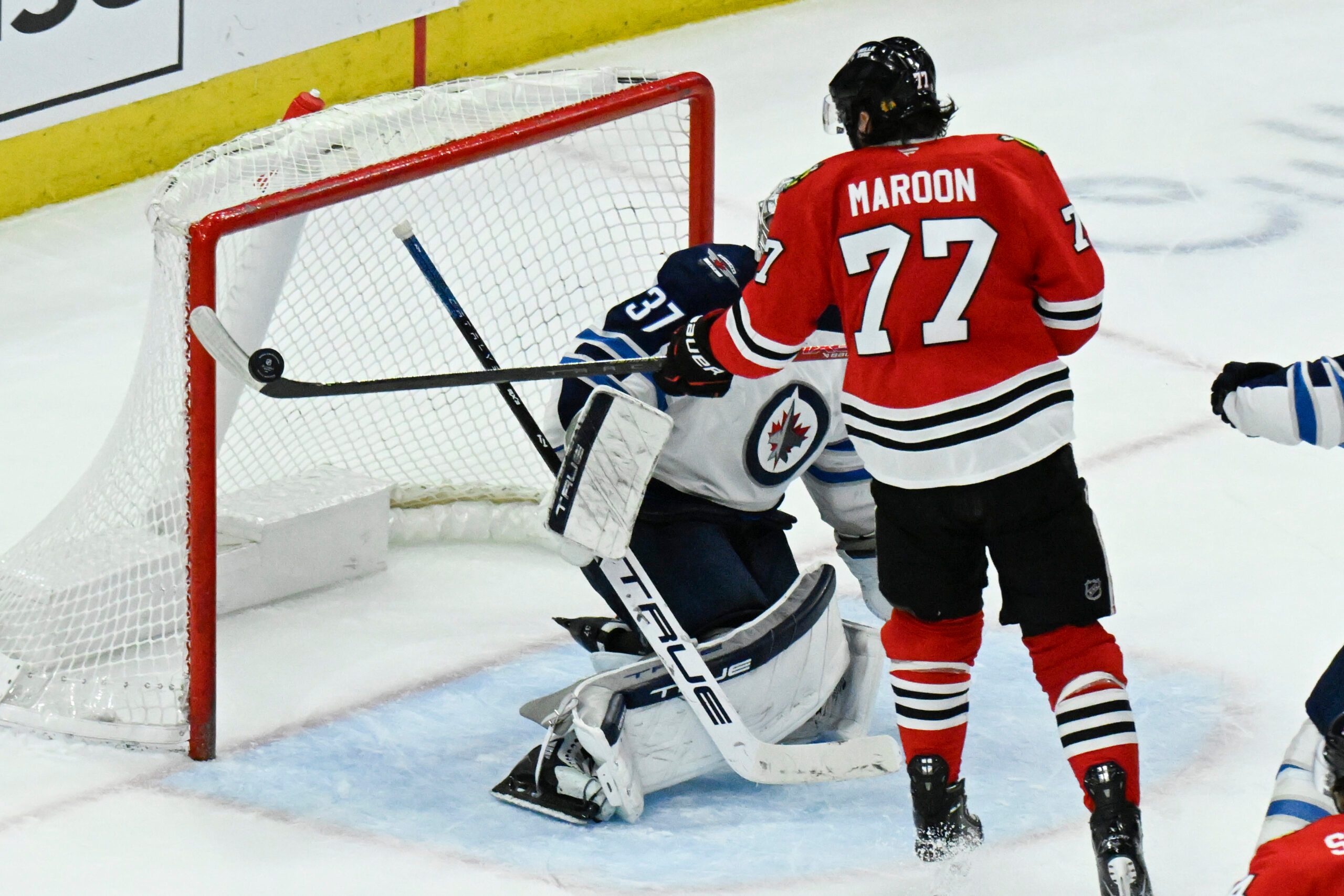 Apr 12, 2025; Chicago, Illinois, USA;  Chicago Blackhawks left wing Patrick Maroon (77) rises a shot against Winnipeg Jets goaltender Connor Hellebuyck (37) during the third period at United Center. Mandatory Credit: Matt Marton-Imagn Images