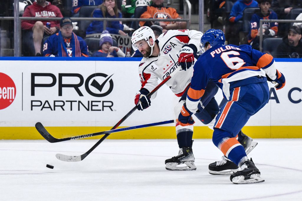 Apr 15, 2025; Elmont, New York, USA; Washington Capitals right wing Tom Wilson (43) takes a shot on goal as New York Islanders defenseman Ryan Pulock (6) defends during the first period at UBS Arena. Mandatory Credit: John Jones-Imagn Images