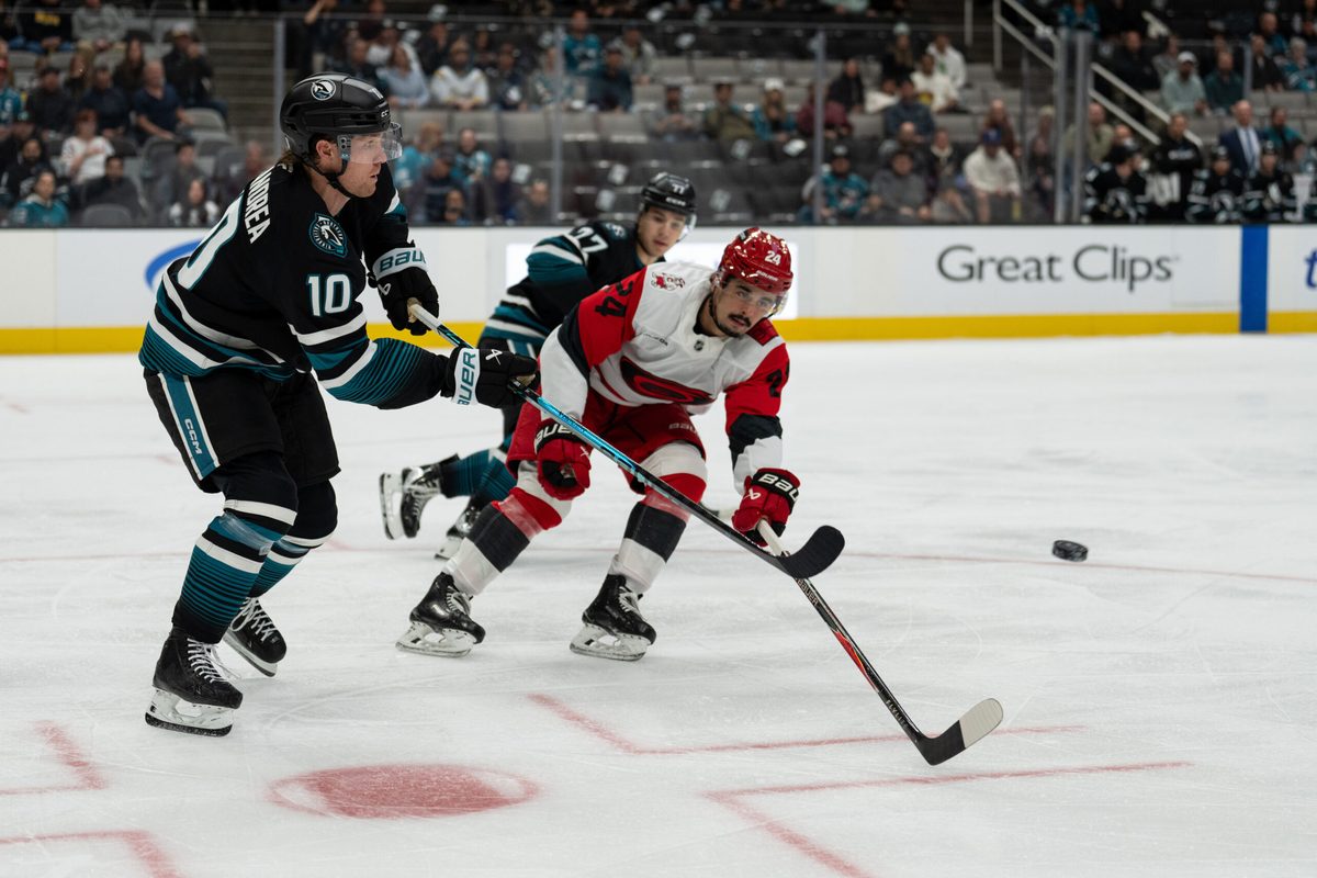 Oct 14, 2025; San Jose, California, USA; San Jose Sharks center Ty Dellandrea (10) shoots the puck past Carolina Hurricanes center Seth Jarvis (24) during the first period at SAP Center at San Jose. Mandatory Credit: Stan Szeto-Imagn Images