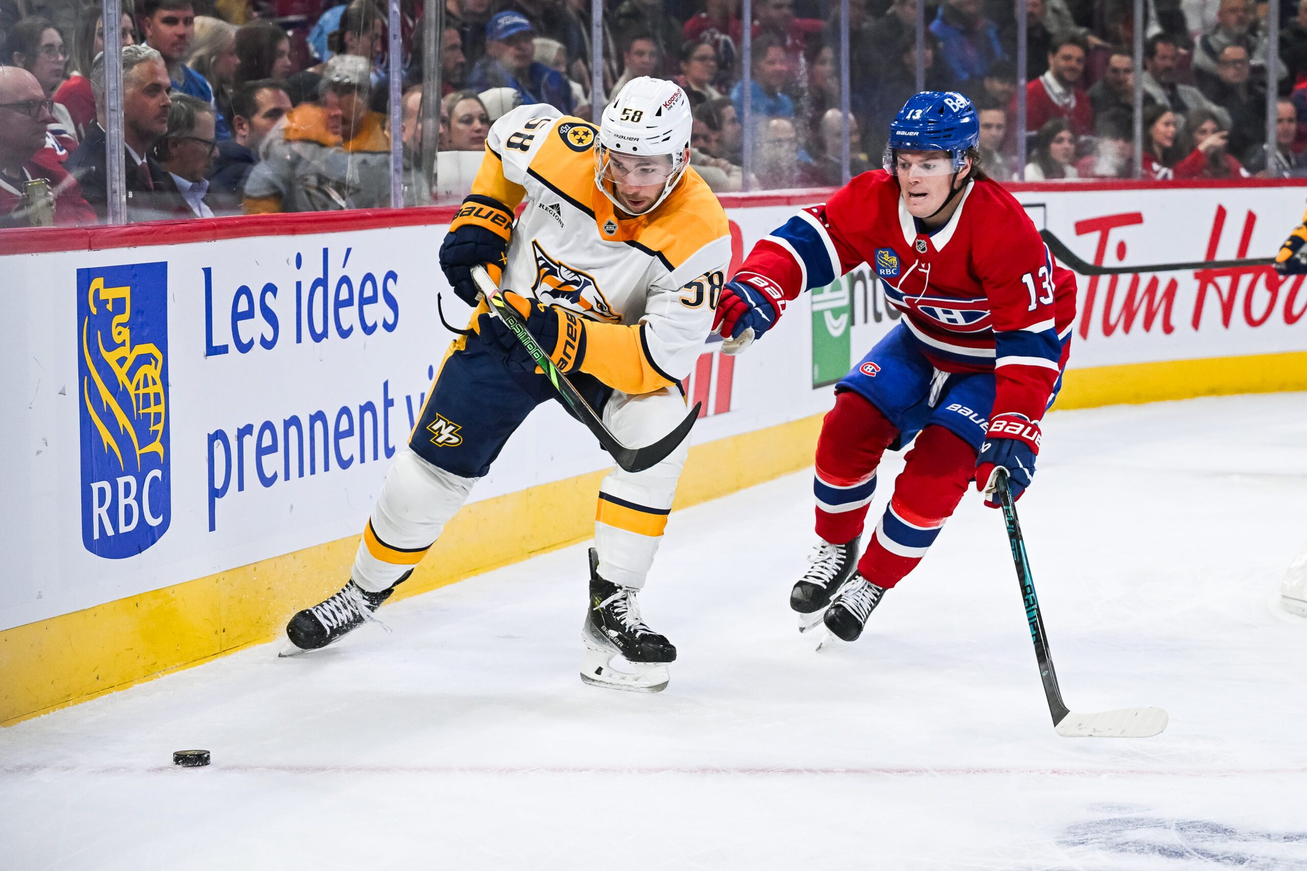 Oct 16, 2025; Montreal, Quebec, CAN; Nashville Predators left wing Michael Bunting (58) plays the puck against Montreal Canadiens right wing Cole Caufield (13) during the first period at Bell Centre. Mandatory Credit: David Kirouac-Imagn Images