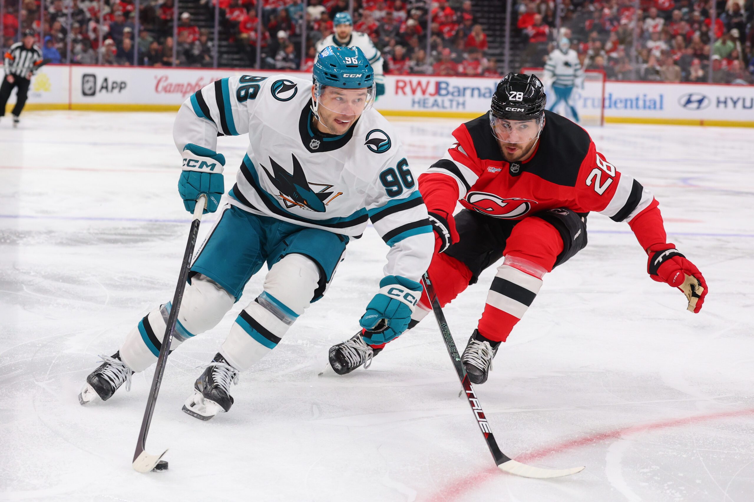 Oct 24, 2025; Newark, New Jersey, USA; San Jose Sharks center Philipp Kurashev (96) skates with the puck as New Jersey Devils right wing Timo Meier (28) defends during the third period at Prudential Center. Mandatory Credit: Ed Mulholland-Imagn Images